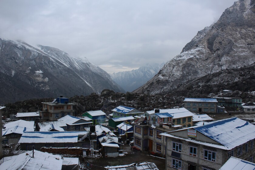 A town in Nepal with snow-covered mountains in the background.