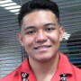 Michael Tejada's smiling headshot with red aloha shirt and kukui nuts lei with grey background.