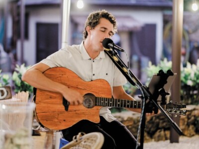 Braden Wood sings into a microphone while playing a guitar