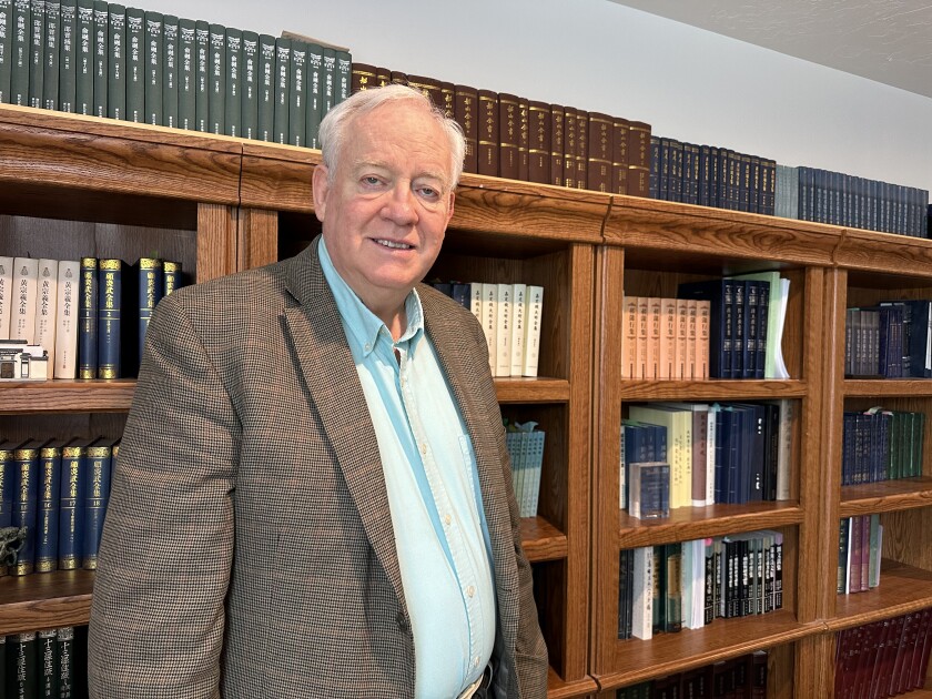David Honey smiling in front of his bookshelves at home.