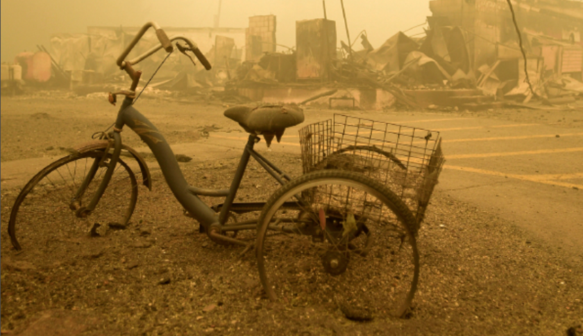 Photo of a burned down town and bike all in brown smoke haze.