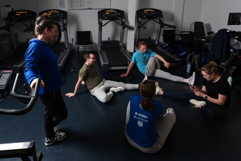 A woman guides a group of students in stretches