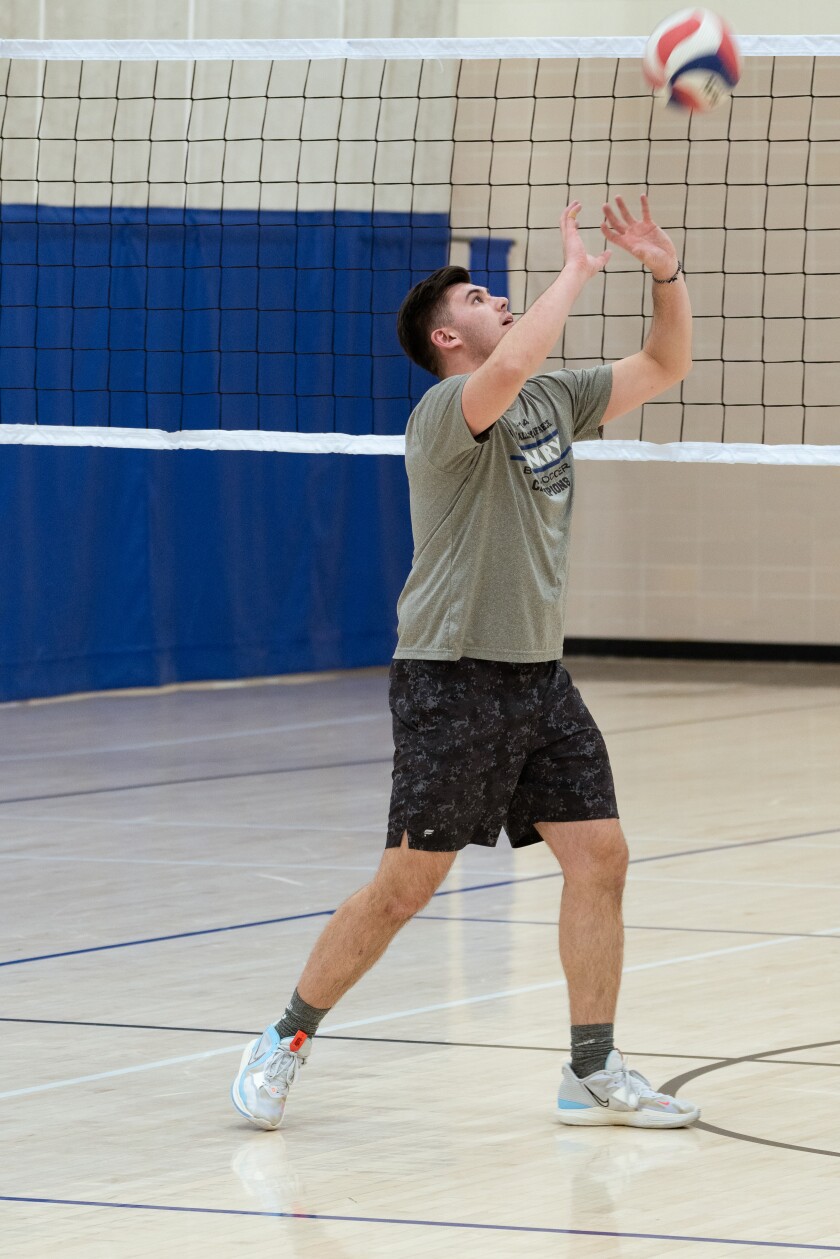 Parker Dean stands in setting volleyball stance wearing a green shirt and black shorts. 