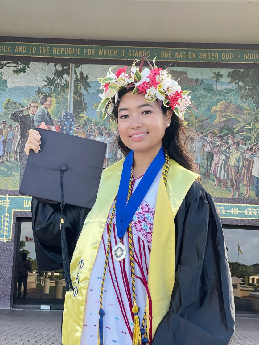 Cindy Shee standing outside while wearing graduation cap and gown.