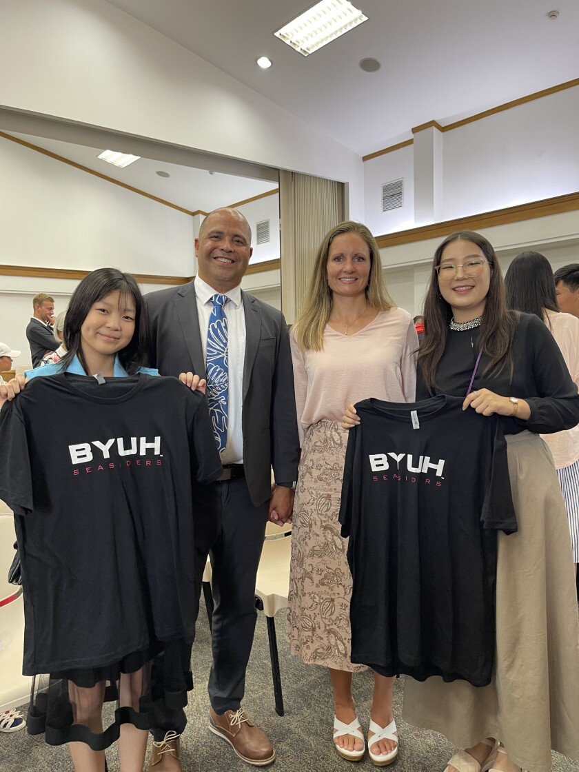 President and Sister Kauwe standing with church youth in Mongolia. The two female youth are holding up BYUH branded t-shirts.