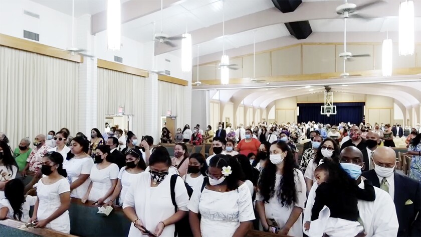 People wearing white, and face masks due to the pandemic, fill the Laie Stake Center.