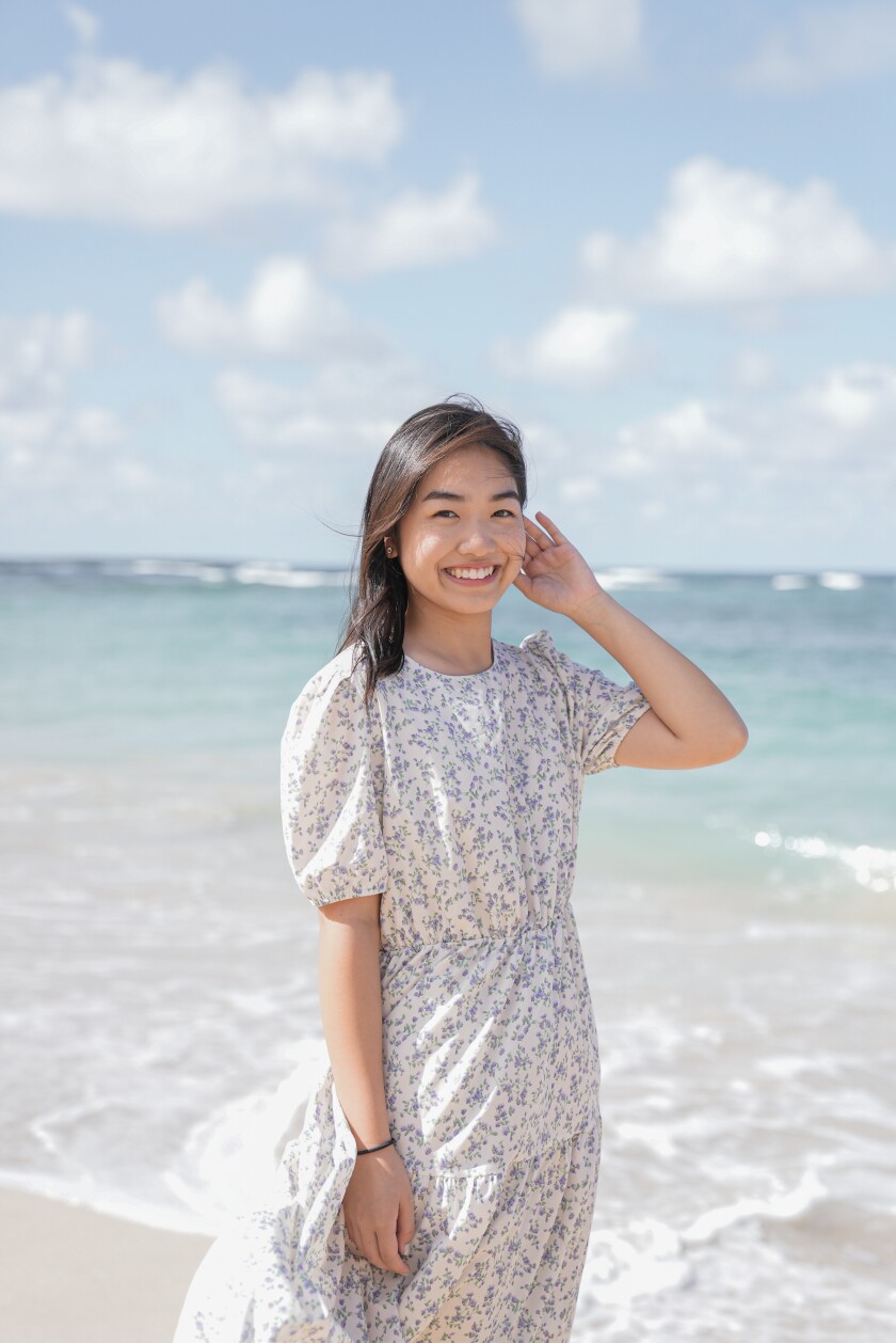 A woman stands outside at the beach with wind blowing her hair.
