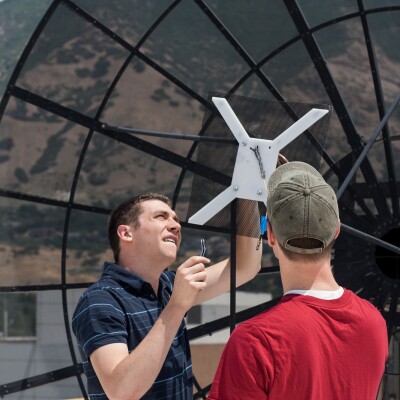 An image of two men working on a project by a satellite dish