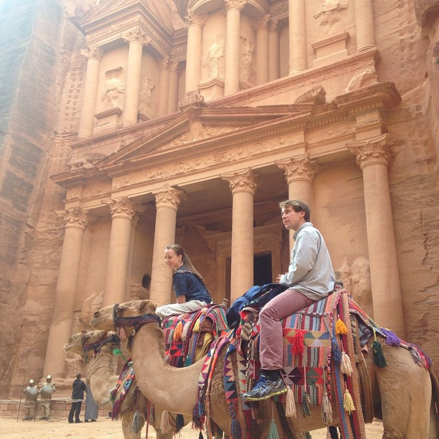 A man and woman on camels near the entrance of the temple at Petra