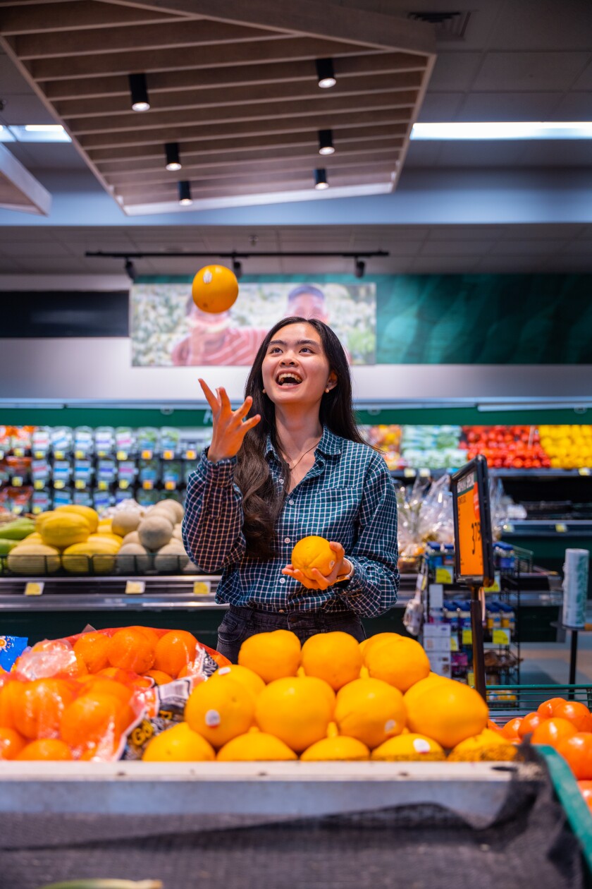 Jessika Santoso holding oranges in her hands at Foodland