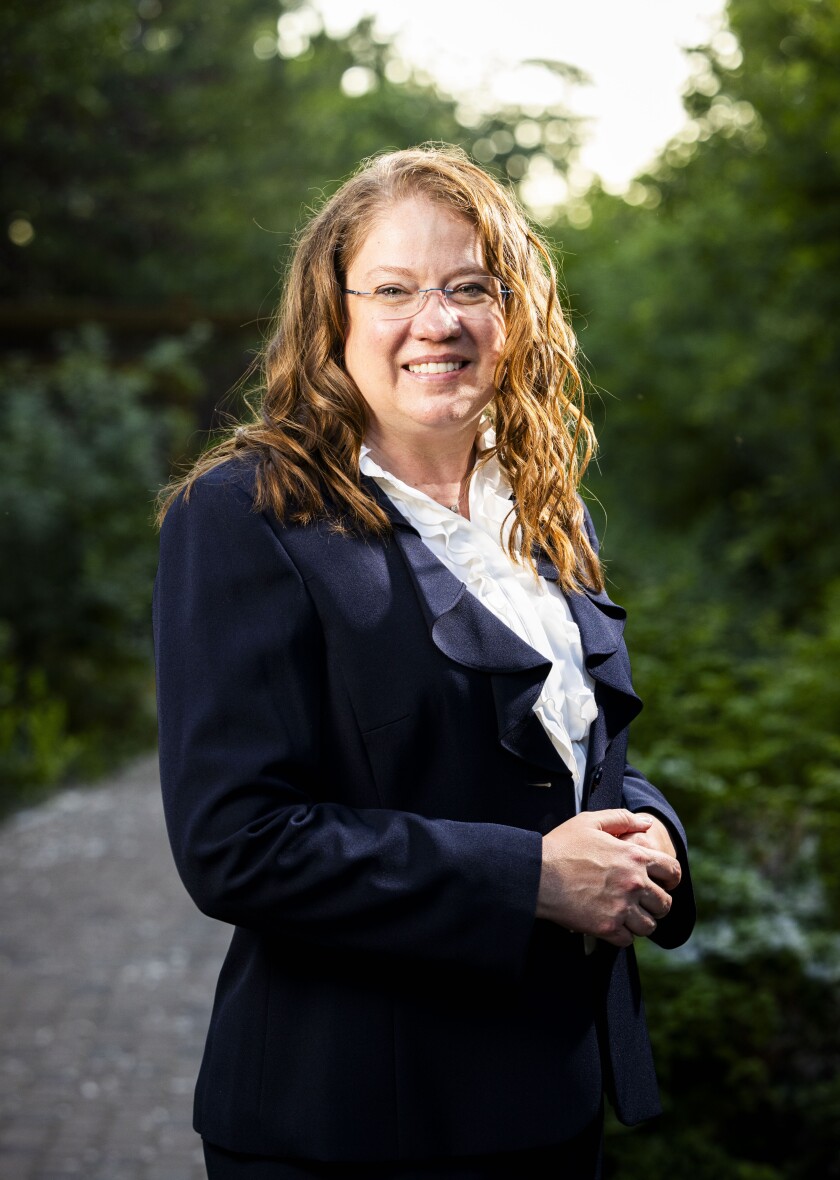 Pamela Brubaker poses for a photo with arms clasped in front of her. She is smiling at the camera.