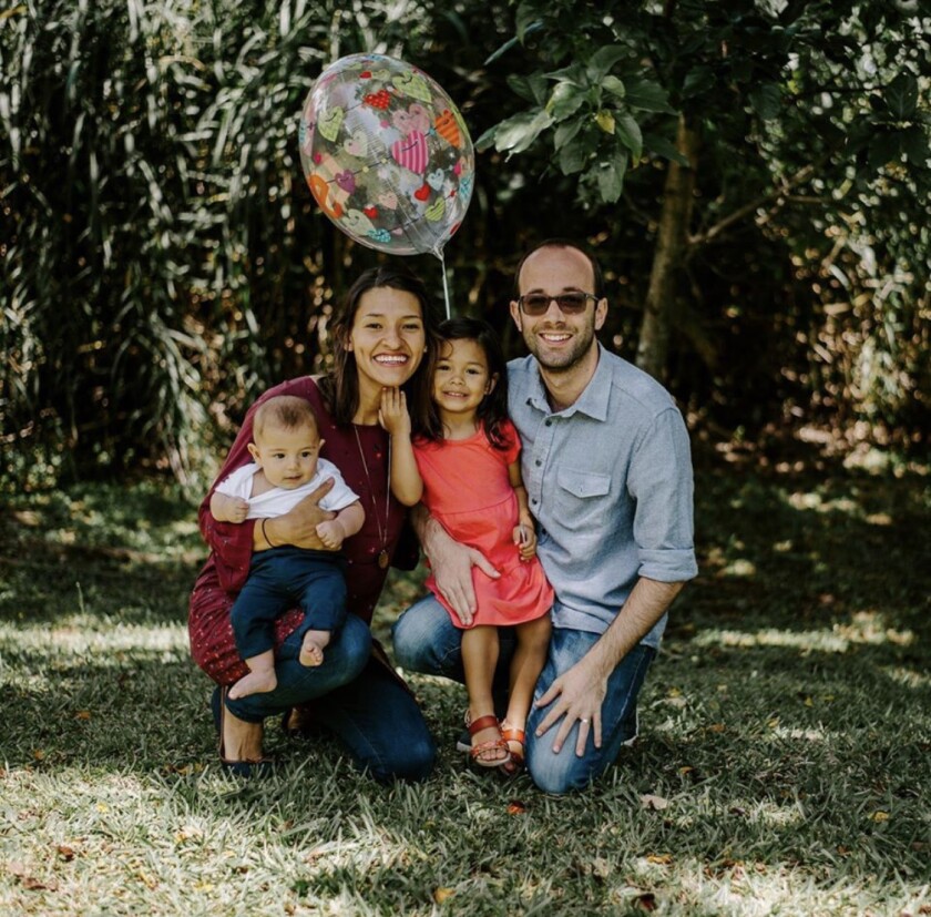 Carlos Speranza kneels in the shade with his wife and two kids with a balloon hovering above them