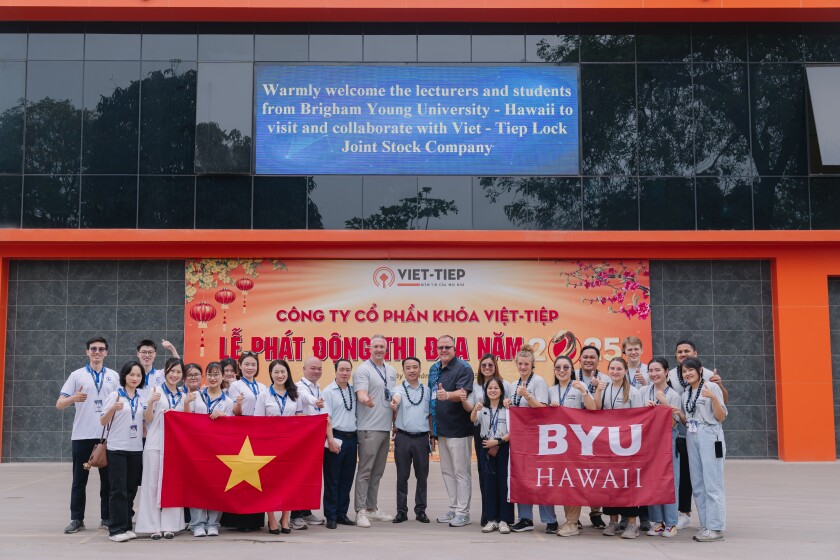 BYUH students with Viet - Tiep Company posing for a photo with the BYUH flag and the Vietnam flag in display