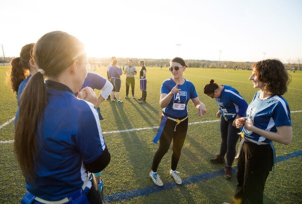 Three faculty members talk on the sideline during their flag football game
