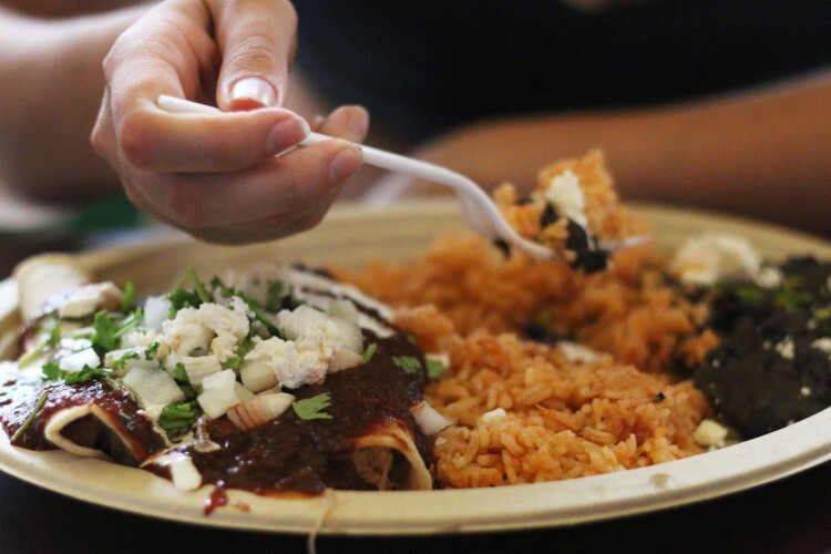 A plate of enchiladas, rice, and beans