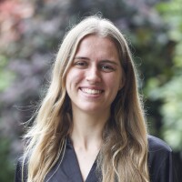 Shaye Swaney's smiling headshot with green outdoor blurred background.