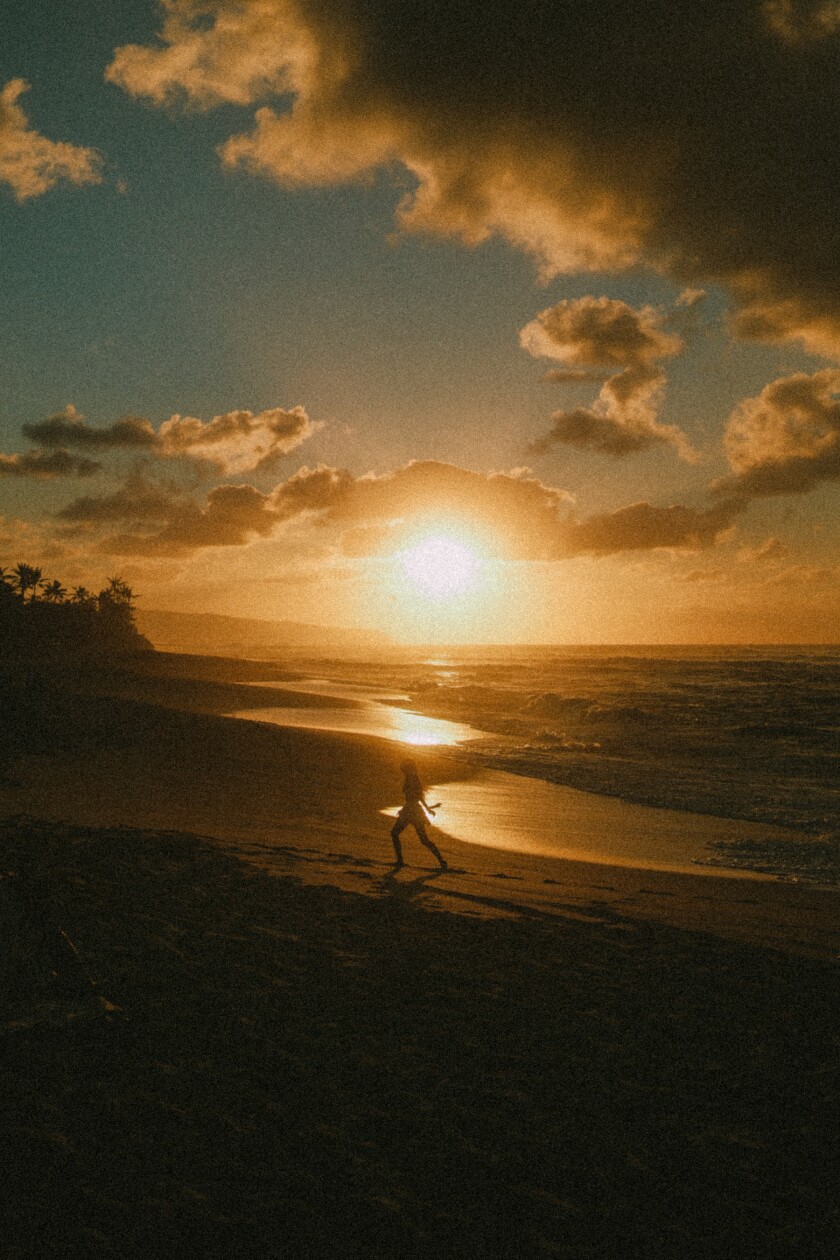 A girl running on the shore of Sunset beach during sunset.