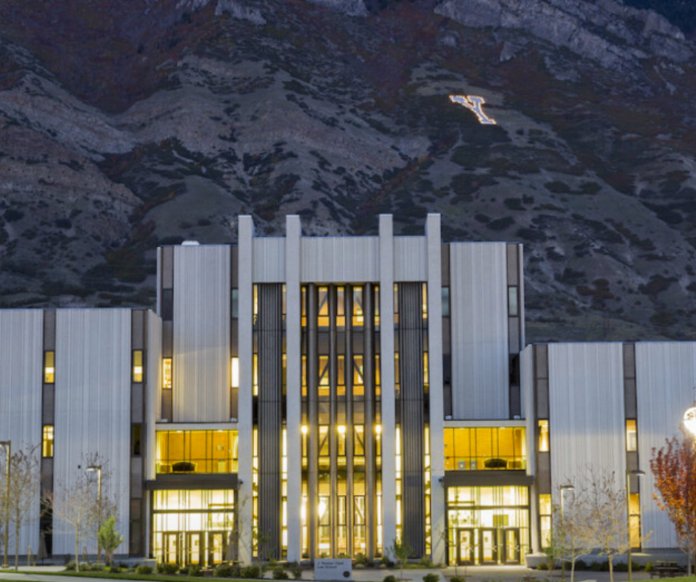 Front of the BYU Law School building during night with the mountains in the bakground.