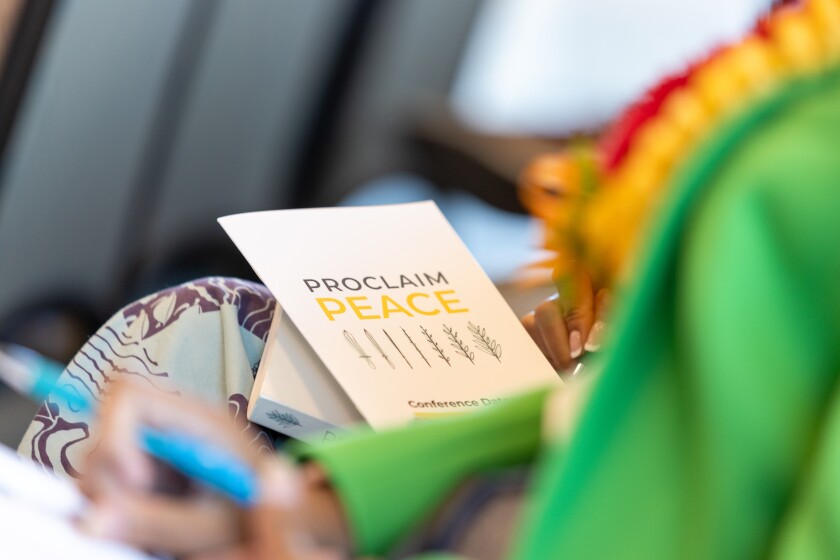 A close-up shot of the program for the Proclaim Peace Conference that is being held on a woman's lap.