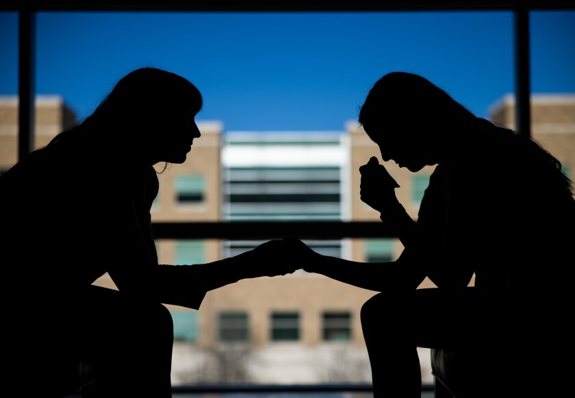 shadow of a female student leaning forward providing comfort to another student