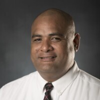 Victor Kaufusi is shown wearing a white shirt and dark tie.