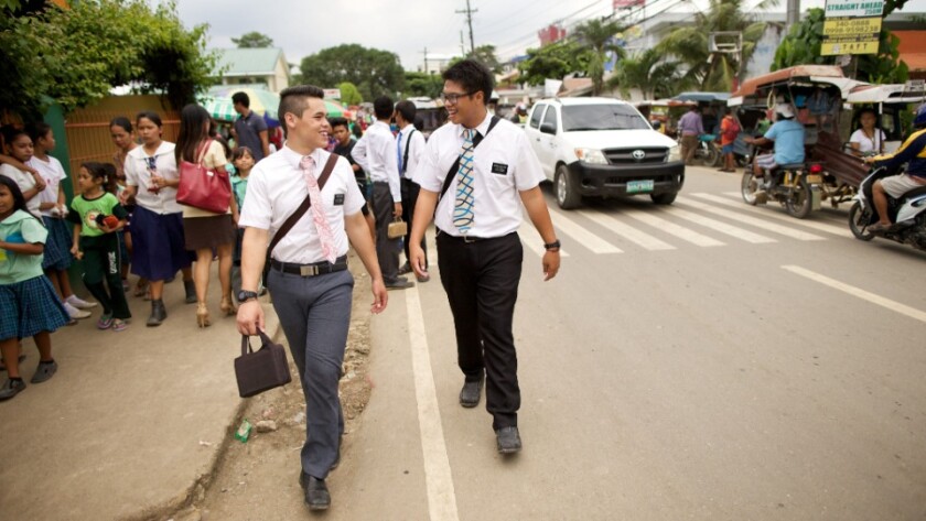 Two male missionaries walk along a street in the Philippines.