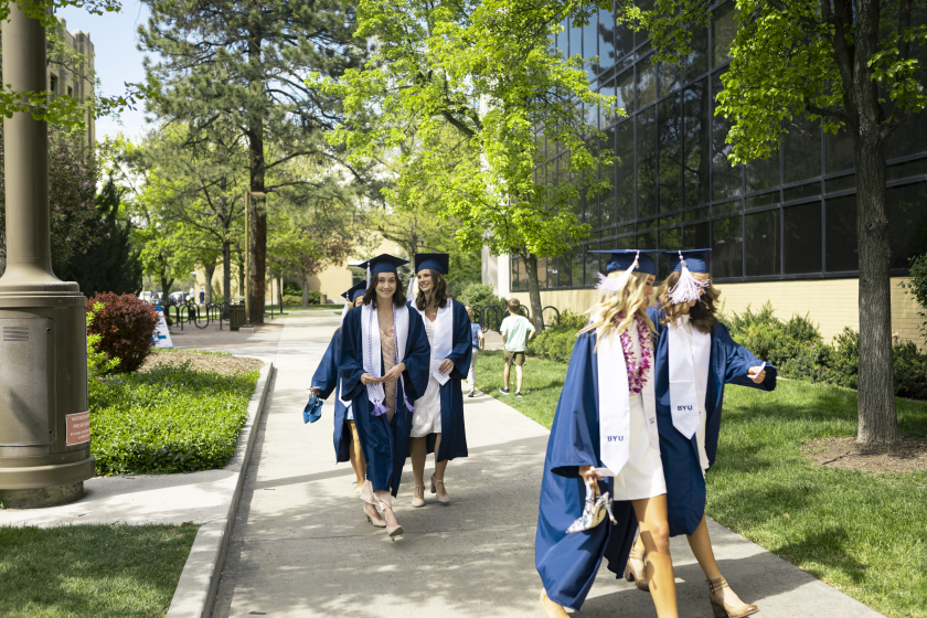A group of young women in graduation robes walks up a hill