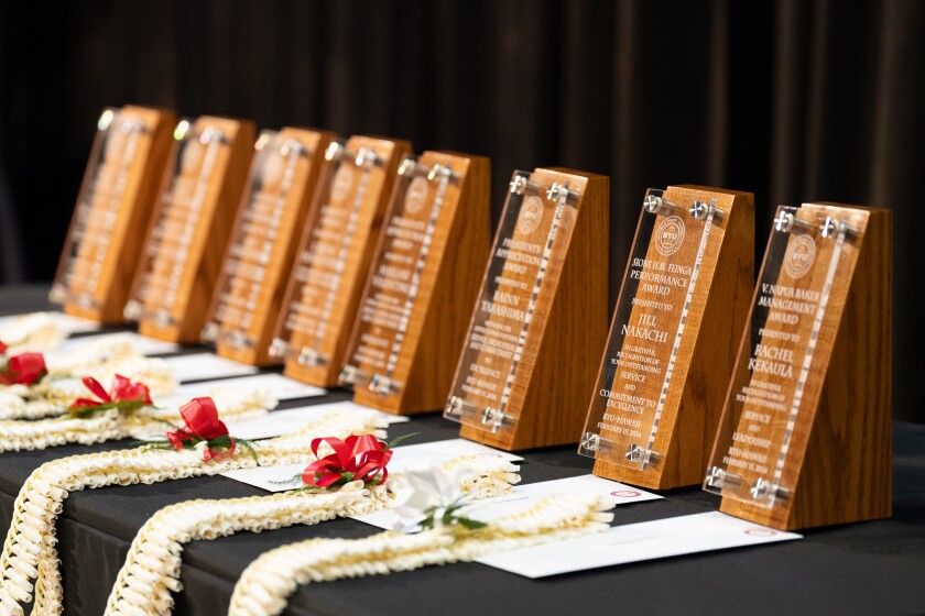 A line of plaques laid out along with leis and envelopes.