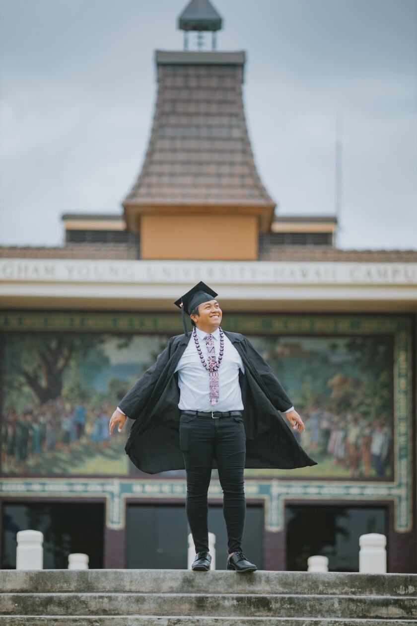Zaphnath Villanueva standing outside wearing a graduation cap and gown.