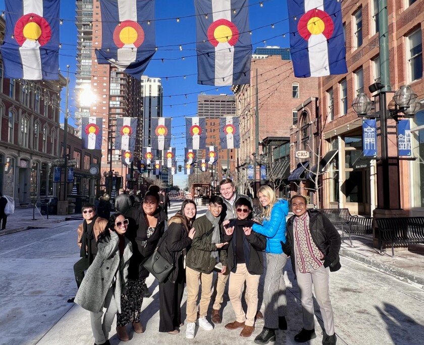 Students smiling and Denver flags hanging with string lights.