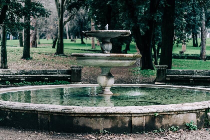 A large decorative fountain with water flowing over the edges into the lowest ground level basin.