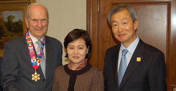Nelson with a gold medal with flags around the lanyard standing next to Korean Ambassador Ahn Ho-Young and his wife, Seon Hwa Lee.