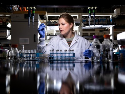 A woman examines a test tube in a lab.