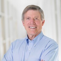 Jeffrey Hill's smiling headshot with blue shirt and white blurred background.