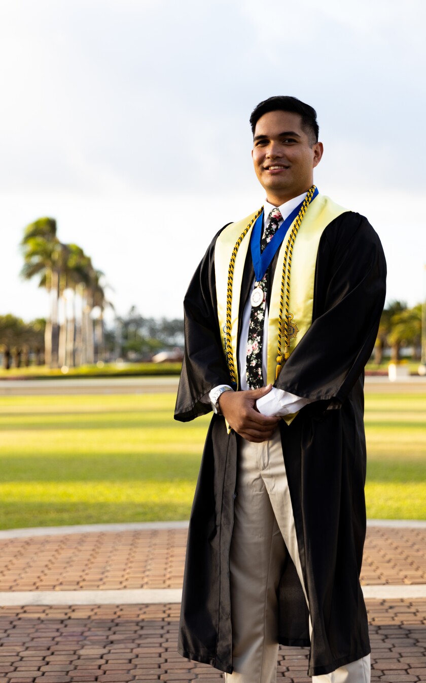 Vaughn standing outside wearing graduation gown.