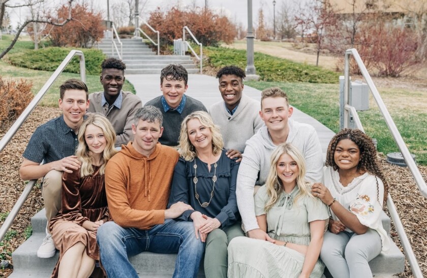 The Rogers family sitting on a pavement, smiling for a photo