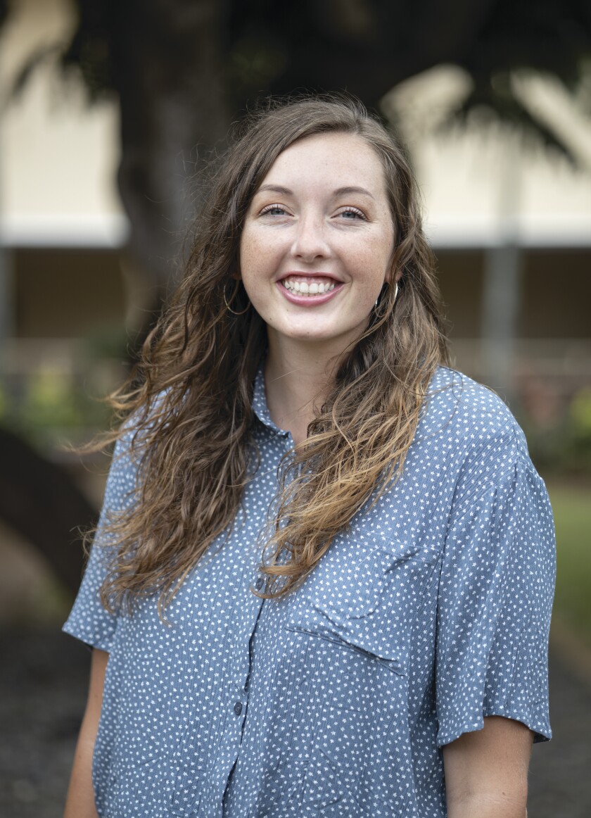 portrait shot of young woman wearing blue and white button-up shirt smiling for the photo