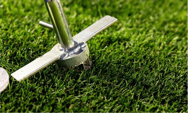 A metal tool is inserted into the grass