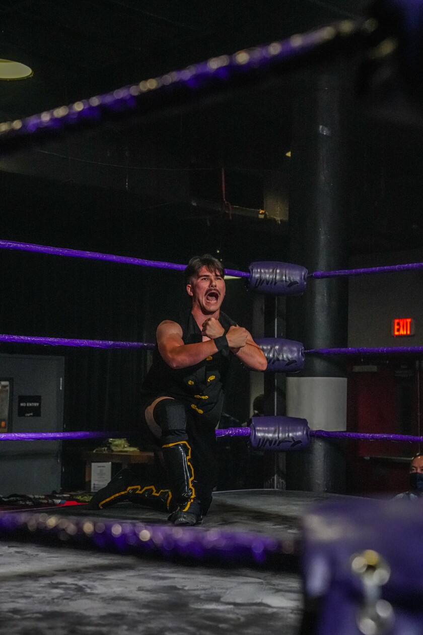 A wrestler in the wrestling ring yells with his arms across his chest.