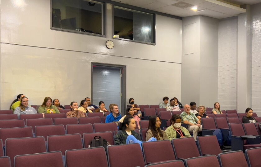 People are sitting and listening to a speaker.