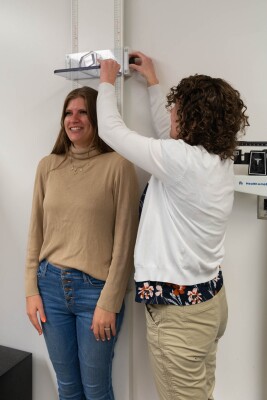 Dr. Bellini measures a student's height with a white drop-down measuring tool.