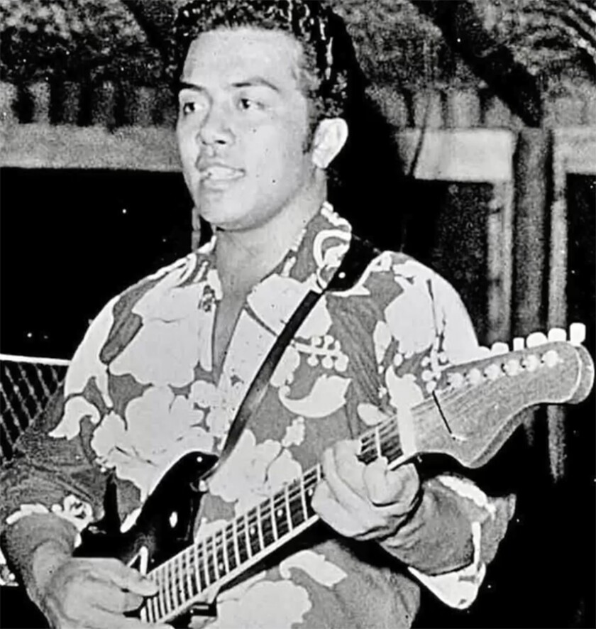 Pulefano Galea'i sings wearing a Hawaiian shirt and playing the guitar.