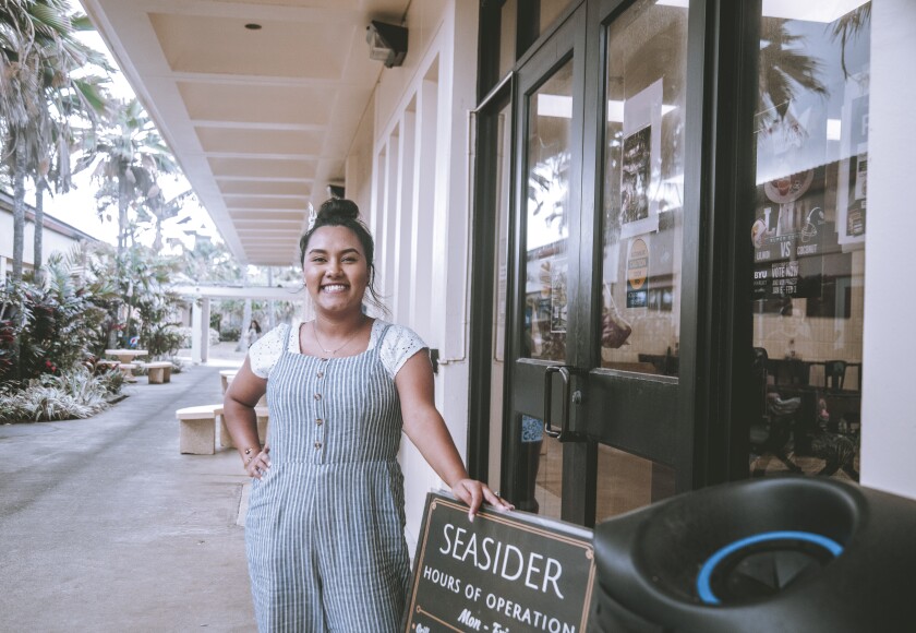 Aline Ly stands in front of a sign outside of the Seasider.