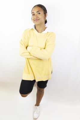 portrait shot of female model wearing a yellow long-sleeved shirt and biker shorts