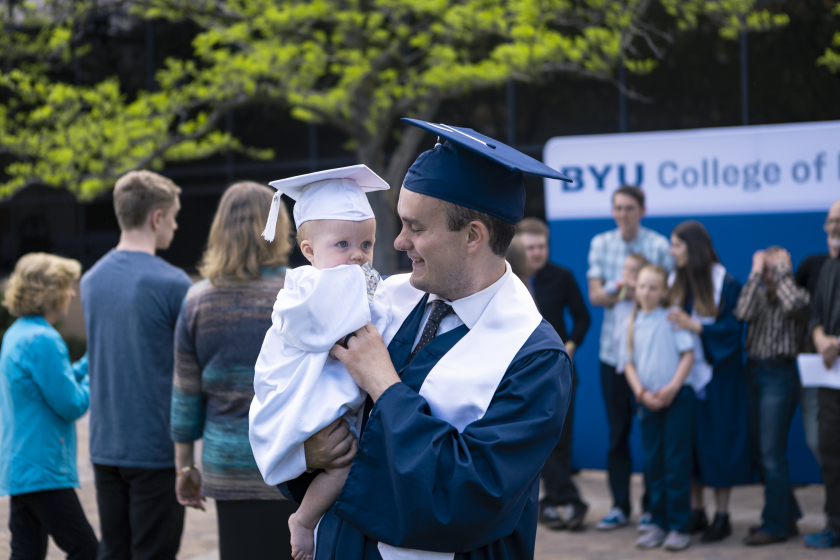 A nursing graduate holds a young child