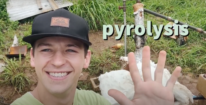Screenshot of the video presentation with Sterling Kerr smiling waving wearing a black hat with the word "pyrolysis" on the screen and grass and metal behind him.
