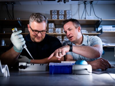 Professor teaches a student how to pipette in lab.