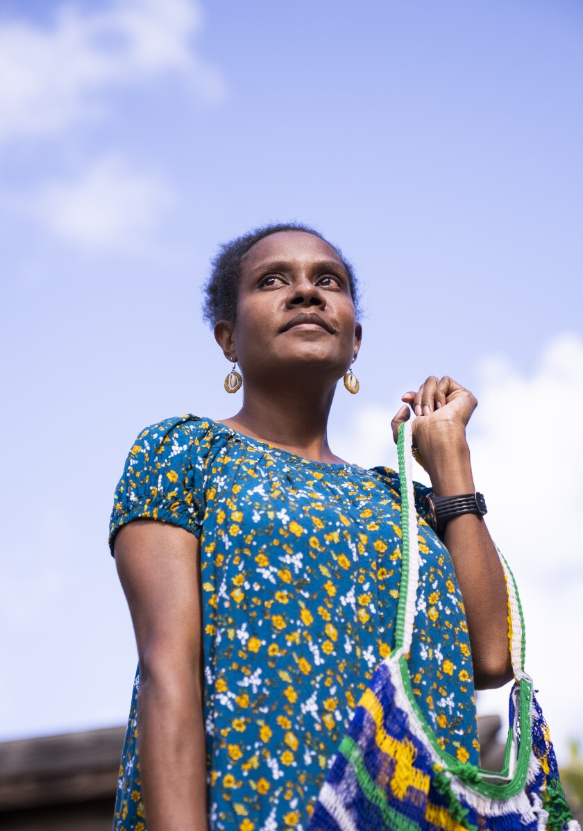 A woman in a colorful dress holds a bag.