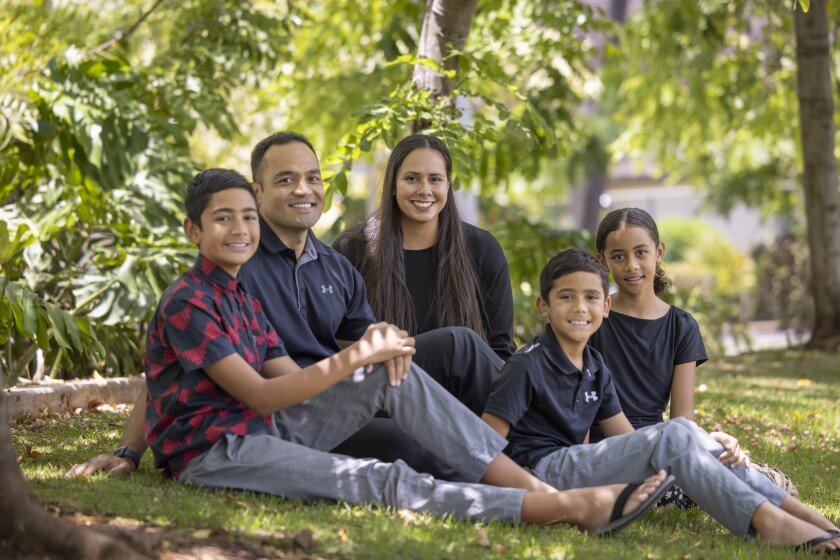 Tialei with her family sitting on the grass.