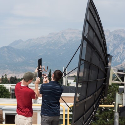 An image of two men working close by a satellite